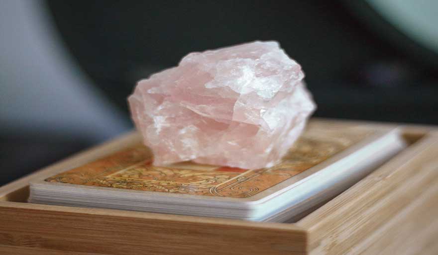 pink quartz crystal on a tarot deck