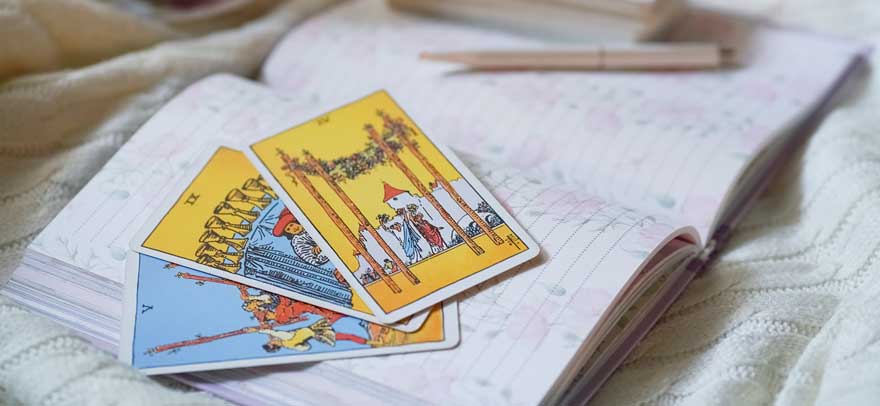 tarot cards and a notebook on a bed